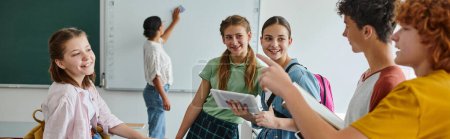 Photo for Schoolboys talking and pointing near friends and blurred african american teacher in class, banner - Royalty Free Image