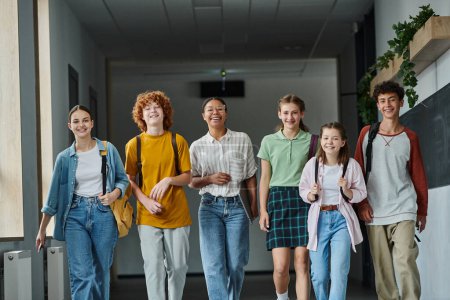 retour à l'école, diversité culturelle, enseignant heureux et adolescents marchant dans le couloir de l'école