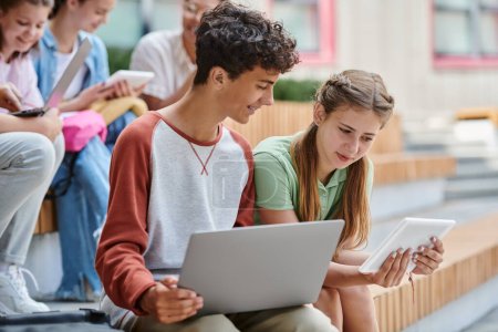 zurück zur Schule, Teenie-Mädchen zeigt glücklichen Jungen digitales Tablet, Diversität, Lehrer und Schüler, Unschärfe