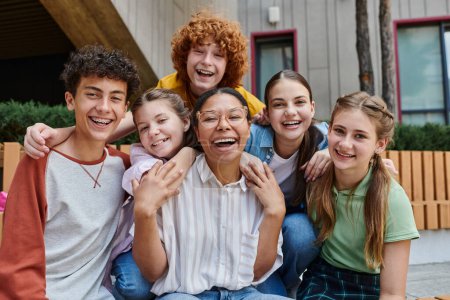 Photo for Cultural diversity, back to school happy african american teacher hugging with teen kids, education - Royalty Free Image