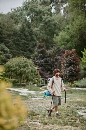 Téléchargez les photos : Joyeux routard indien tenant des bâtons de trekking sur le chemin dans la forêt, Voyage et concept d'aventure - en image libre de droit