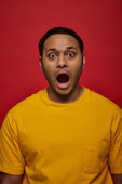 shock expression, indian man in yellow clothes looking at camera with open mouth on red backdrop puzzle #670404534