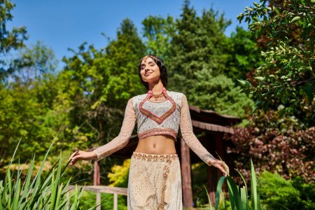 pleased authentic style indian woman with closed eyes enjoyment walk in summer park