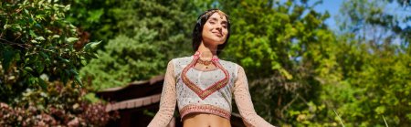 Téléchargez les photos : Sortie dans un parc d'été, femme indienne en tenue traditionnelle souriante avec les yeux fermés, plaisir - en image libre de droit