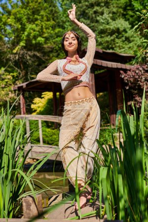 été relax, élégante femme indienne en vêtements traditionnels dansant les yeux fermés dans un parc verdoyant