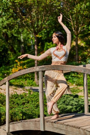 graceful indian woman in authentic style wear dancing in park, summer enjoyment