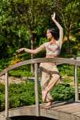 graceful indian woman in authentic style wear dancing in park, summer enjoyment Poster #671993192