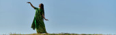 young indian woman in traditional sari in green field under blue and clear sky, summer, banner t-shirt #671993682