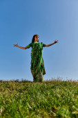 traditional fashion, young indian woman in sari with outstretched hands under blue summer sky Poster #671993884