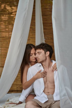 romantisches Paar, schöne Frau umarmt Mann in weißen Kleidern und sitzt in privatem Pavillon