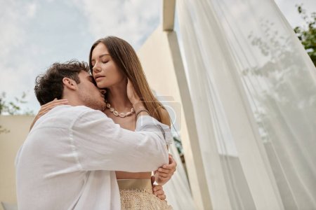 portrait d'un homme embrassant une femme séduisante pendant une escapade romantique en été, geste d'amour