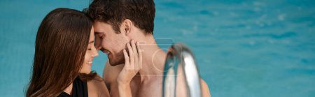 cheerful woman touching face of happy boyfriend in swimming pool, vacation romance, banner