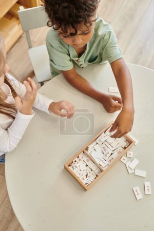 Foto de Aprendizaje de matemáticas, chico afroamericano jugando con chica, escuela montessori, diversos niños, vista superior - Imagen libre de derechos