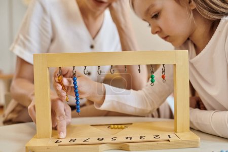 montessori concept, child playing with color bead stairs near teacher, wooden stand, close up