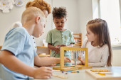 cute kids looking at african american boy playing educational game in montessori school, diversity puzzle #672161742