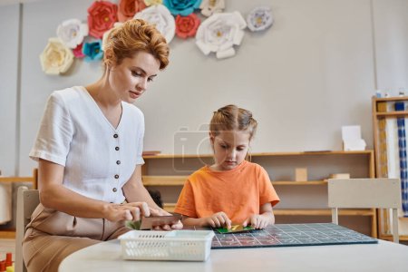 Téléchargez les photos : Fille intelligente comptage près enseignante, tableau, apprendre à compter dans l'école Montessori - en image libre de droit