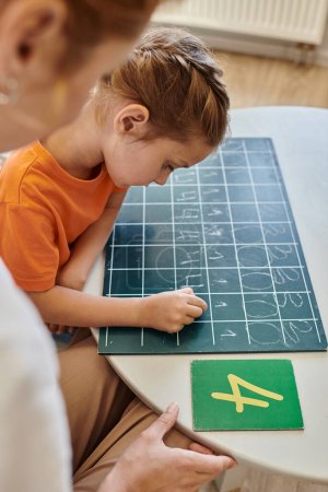 profesora observando a una chica inteligente en la escuela Montessori, contando, escribiendo en pizarra, números