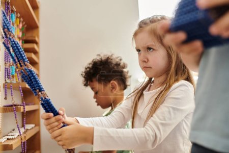 stubborn girl pulling beads near interracial kids, diversity, Montessori school concept, discover