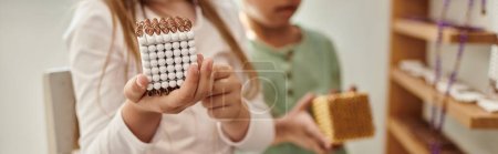 cropped girl holding cube with beads near african american boy, diversity, Montessori school, banner