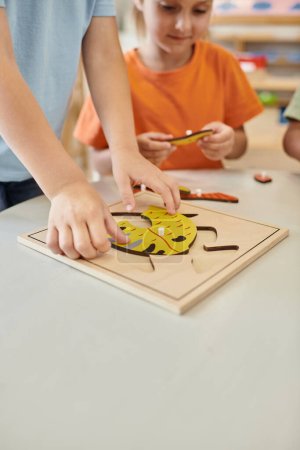 interrassische Kinder, die in der Schule mit didaktischem Montessori-Material spielen, lernen und spielen, Jungen und Mädchen