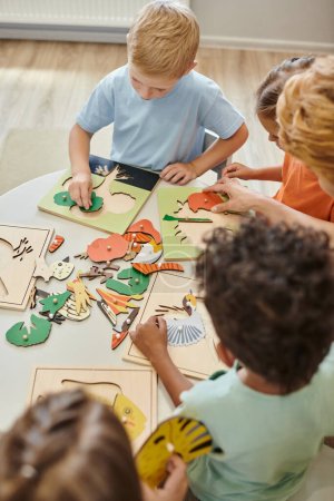 Overhead-Ansicht multiethnischer Kinder und Lehrer mit didaktischen Materialien in der Montessori-Schule