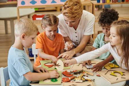 Lehrer spielt in Montessori-Schule mit interrassischen Kindern mit didaktischen Materialien
