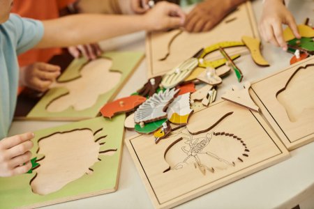 abgeschnittene Ansicht von interrassischen Kindern, die mit didaktischen Materialien auf dem Tisch in der Montessori-Schule spielen