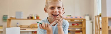 fröhlicher Junge mit Dreiecken beim Spiel im Klassenzimmer der Montessori-Schule, Transparent