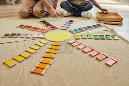 cropped view of colorful bricks near blurred african american boy and teacher in montessori school