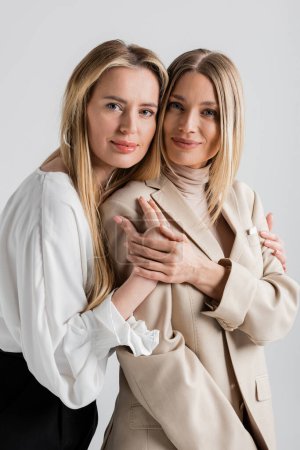 portrait of two stylish cute sisters hugging each other and looking at camera, fashion concept