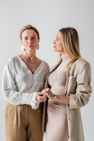 stilvolle attraktive Schwestern in Business Casual und Pastellkleidung Händchenhalten, Modekonzept