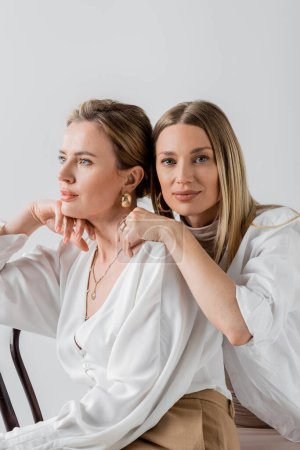 Téléchargez les photos : Portrait de deux sœurs à la mode dans un élégant costume pastel formel étreignant, style et mode - en image libre de droit