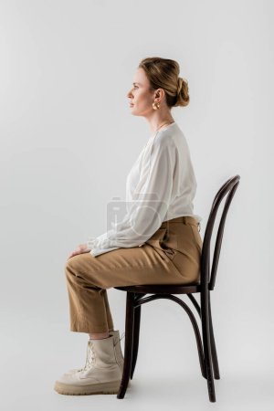 mujer joven y elegante sentada en una silla con atuendo de pastel formal de moda, estilo y moda