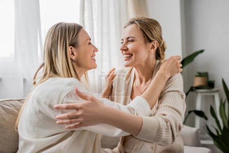 Photo for Lovely pretty sisters in trendy attire smiling looking at each other and hugging, family bonding - Royalty Free Image