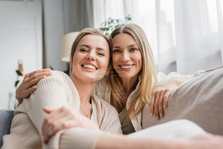 Photo for Two cheerful trendy sisters in pastel cardigans smiling sincerely at camera, family bonding - Royalty Free Image