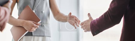 partial view of successful business partners shaking hands in office, closing deal, banner