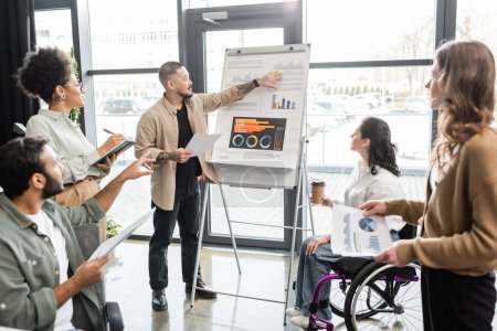 Photo for Inclusion, asian man showing charts and graphs and planning work with team and woman in wheelchair - Royalty Free Image