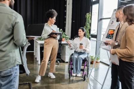 concept d'inclusion, femme handicapée en fauteuil roulant partageant des idées avec des hommes d'affaires interracial