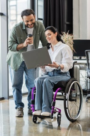 feliz empresario indio discutiendo proyecto de startup con mujer discapacitada en silla de ruedas, inclusión