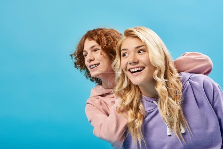 Unbekümmerte Teenager-Freunde in stylischer Freizeitkleidung lächeln und schauen weg auf Blau, Glück