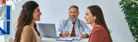 Photo for Happy lesbian couple looking cheerfully at each other during doctor appointment, ivf concept, banner - Royalty Free Image