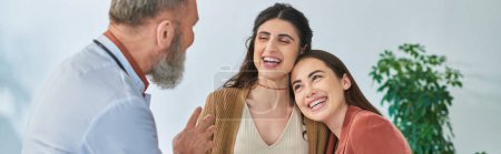 Photo for Happy lesbian couple hugging and looking at their gynecologist, in vitro fertilizing concept, banner - Royalty Free Image