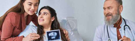 joyous lesbian couple hugging warmly looking at ultrasound with doctor aside, ivf concept, banner