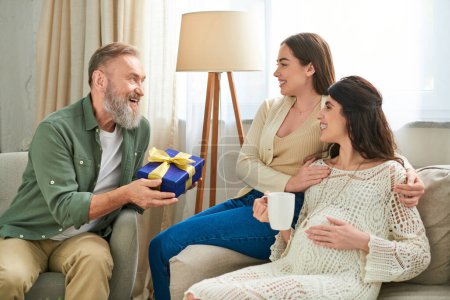 alegre padre visitando a su hija embarazada y su pareja y dándoles un regalo, concepto ivf