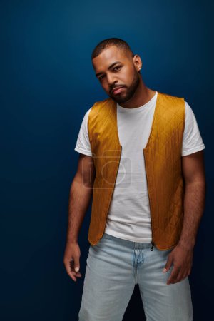 stylischer bärtiger afrikanisch-amerikanischer Mann mit gelber Weste blickt in die Kamera, Modekonzept