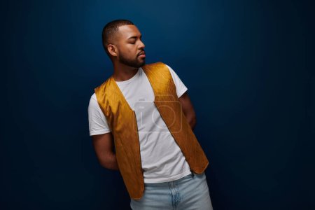 Photo for Young african american man in stylish yellow vest posing bending over to side, fashion concept - Royalty Free Image
