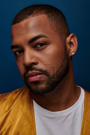 portrait of handsome stylish man with beard and diamond earring looking at camera, fashion concept