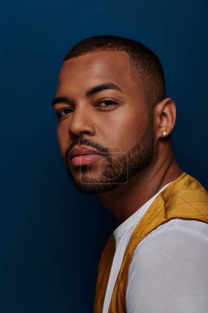 handsome african american man with beard and diamond earring looking at camera, fashion concept