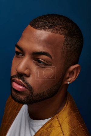 Téléchargez les photos : Portrait de jeune homme élégant avec boucle d'oreille en diamant et barbe détournée, concept de mode - en image libre de droit