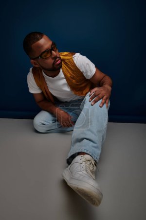 gutaussehender Afroamerikaner in Sonnenbrille, gelber Weste und Jeans, Modekonzept